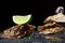 Close-up of beautiful large oysters with ice cube and lime segment on top on a black background. Delicious tropical sea