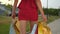 Close-up beautiful legs of young shopping woman female in red dress with bags packages walking outdoors street city