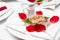 Close-up of a beautiful ready-made dish of meat fillet, red rose petals in a round white plate on the table in a restaurant before