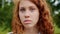 Close-up of beautiful redhead teenager looking at camera with serious face