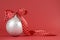 Close up of beautiful white Christmas tree ornament with red polka dot ribbon on red background