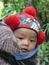 Close up of beautiful, Yao baby baby in hat with red pom poms, Laos