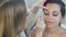 Close-up of a beautiful young brunette came to her makeup artist to make a day make-up. A makeup specialist applies a