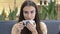 Close-up of beautiful young Caucasian woman drinking coffee from cup and smiling at camera. Gorgeous confident brunette