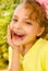 Close up of a beautiful young girl, wearing a yellow t-shirt with colorful dragees in her lips, in a blurred garden