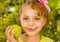 Close up of a beautiful young girl, wearing a yellow t-shirt holding a healthy apple and colorful dragees in her lips