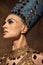 Close-up beautiful young woman in image of Nefertiti in art performance  on brown vintage background. Retro