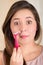 Close up of a beautiful young woman using a shaver pretending to shave her mustache, in a white background