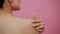 Close-up of a beauty asian young woman massages and apply a cream on her shoulder, on pink background. Beautiful female