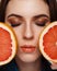 Close-up beauty portrait of young woman with grapefruit with beautiful nude makeup. Modern smokey eyes with colorful eyeshadows