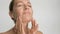 Close-up beauty portrait of young woman with smooth healthy skin, she gently touches her face with her fingers on white