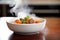 close-up of beef stew in a white bowl, steam rising