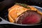 Close-up of beef Wellington cooking in a cast-iron skillet, with seared edges and tender beef on the inside