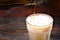 Close up of beer is pouring into a frozen glass from brown bottle on dark wooden desk