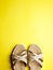 Close up of beige leather summer comfortable women`s sandals on brigth yellow background. Top view, flat lay, vertical