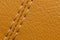 Close-up of beige orange faux leather stitching in the car interior. Background for interior trim comfort