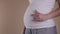 Close up belly pregnant woman do rock symbol. Pregnant hugging tummy at home. Motherhood concept. Baby Shower