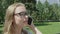 Close up of bespectacled attractive girl with blonde hair answering to a phone call and nodding approvingly sitting on