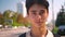 Close-up beutiful face og asian guy looking at camera relaxed and standing near highway, city life, warm sunny day