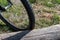 Close-up of a bicycle wheel parked by an old big log