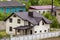 Close-up of big new comfortable two-storied new cottage with green tile roof, big yard, plastic windows and high chimneys in mode