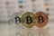 Close up of Bitcoins, gold bitcoin, silver bitcoin and bronze bitcoin with blurred background of world flags. reflection