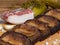 Close-up black bread toasts with bacon on wooden background with garlic, salt and spices