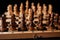 Close up of black chess pieces on board. Two rows of wooden figures on chessboard on black background. Concept of