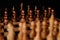 Close up of black chess pieces on board. Two rows of wooden figures on chessboard on black background. Concept of