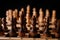 Close up of black chess pieces on board. Two rows of wooden figures on chessboard on black background. Concept of