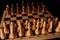 Close up of black chess pieces on board. Two rows of wooden figures on chessboard on black background. Concept of