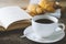 Close up of black coffee with book and croissant on wooden table