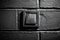 Close-up of black electric switch button on brick textured wall.