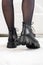 Close-up black elegant shoes on women& x27;s legs. Leather winter boots, stylish lady footwear concept