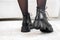 Close-up black elegant shoes on women& x27;s legs. Leather winter boots, stylish lady footwear concept