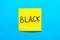 Close up black handwritten inscription black on one yellow square sticker on blue background with copy spase