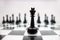 Close up of a black king chess piece on a glossy chessboard on the blurry background of its army