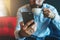 Close-up of black smartphone in man`s hand. In background, in soft focus, young bearded businessman drinks coffee.