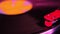 Close-up of black vinyl record, disk is spinning, colored lights, analogue retro music concept, audio experience, relaxation,