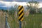 Close up of black and yellow diagonal stripes road sign beside barbed wire fence