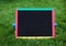 Close-up blank black schoolboard on green grass.Using for insert text. Back to school. Education concept.mockup. Empty chalkboard