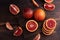 Close up of blood oranges whole, cut into slices and wedges on a dark wooden background, citrus fruit