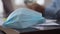 Close-up of blue Covid-19 face mask lying on wooden table with blurred male African American hands gesturing at