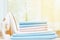 Close-up of blue and white clean bedding on a blurred background. A stack of folded bedsheets on the table, an iron stands nearby.