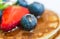 Close up of a blueberry with a drop of honey on the stack of pancakes.