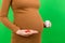 Close up of a bottle and heap of pills in pregnant woman`s hands at colorful background with copy space. Healthy pregnancy concep