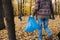 Close up of a bottom part of a man with trash bag in seasonal forest at autumn