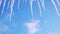 Close up bottom view of melting icicles on blue cloudy sky background. Concept. Early spring natural landscape, end of