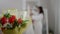 Close-up of bouquet of flowers indoors with blurred young bride taking wedding dress and leaving at background