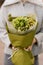 Close-up of bouquet of green hydrangea with sprigs of gypsophila in wrapping paper in female hands